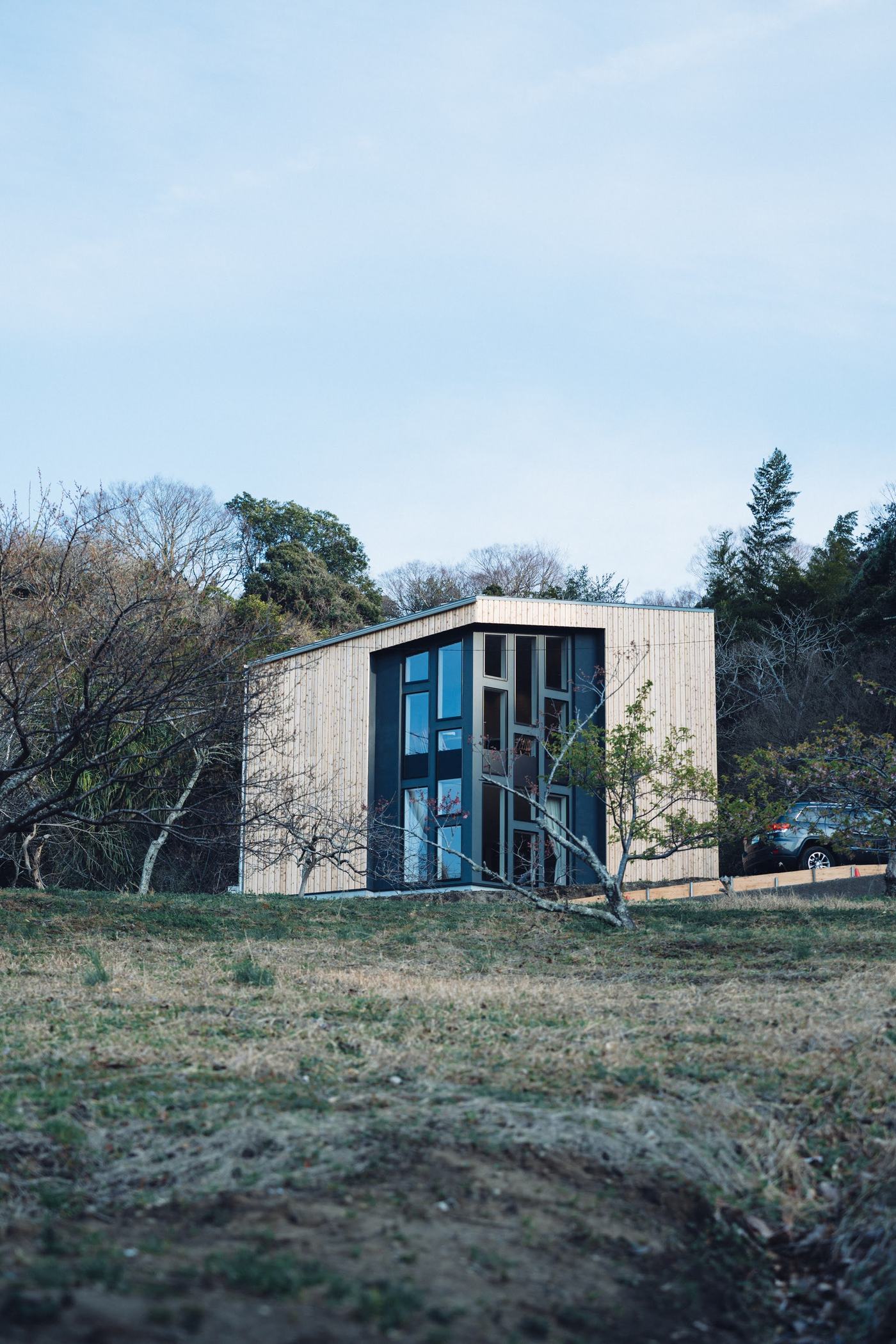 草地の向こうに立つ建物の妻側。縦長の窓が並ぶ
