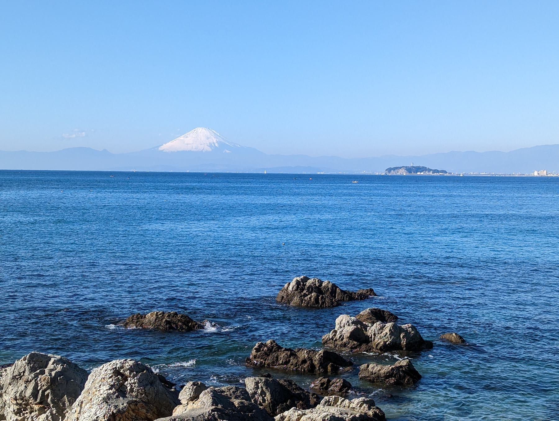 岩場の向こうの海と、遠くに富士山