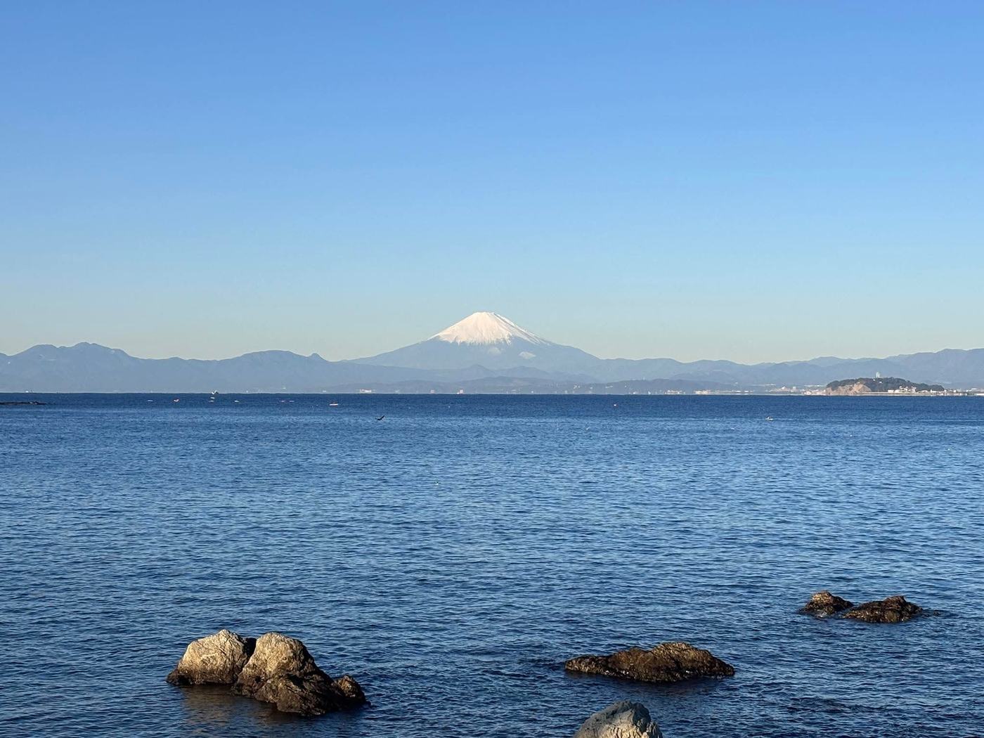 穏やかな海と、対岸に連なる山並みと富士山