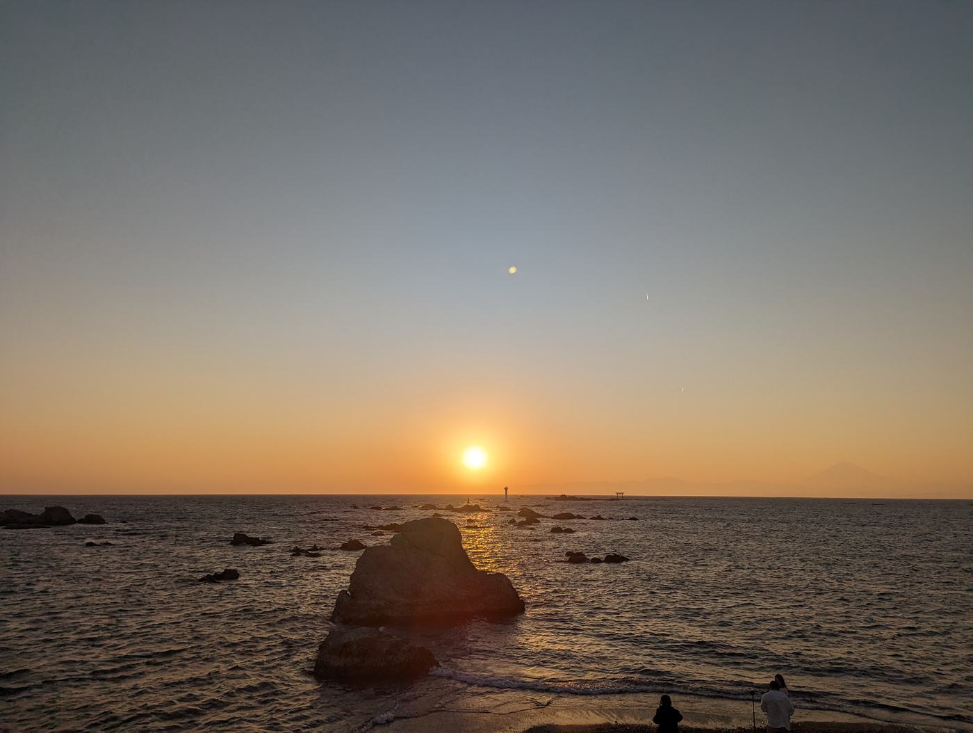 海に沈む夕日と、波打ち際の岩